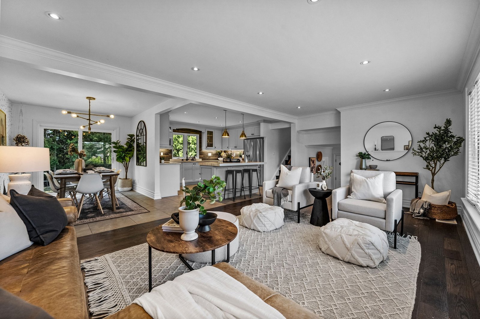 Open-concept living space with a modern kitchen, dining area, and living room featuring neutral colors, wooden floors, and contemporary furnishings.
