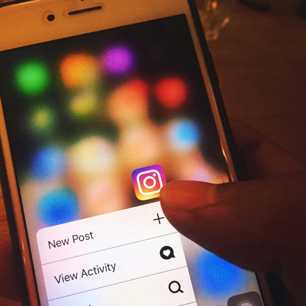 A hand holds a smartphone displaying the Instagram app icon and a menu with options for New Post and View Activity.
