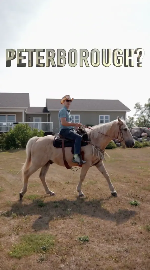 A person wearing a cowboy hat rides a light-colored horse on a dry lawn in front of a house, with large text above reading “PETERBOROUGH?”.